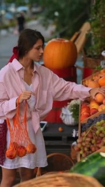 Avrupalı çiftçi pazarındaki büyüleyici genç bayan sürdürülebilirliği somutlaştırarak, çevre dostu bir çantayı meyvelerle dolduruyor. Yüksek kalite 4k görüntü