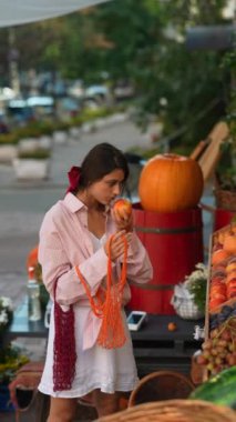 Avrupalı çiftçi pazarı, çevre dostu bir çantaya meyve doldururken çevreyle ilgilenen sevimli genç bir bayanla övünüyor. Yüksek kalite 4k görüntü