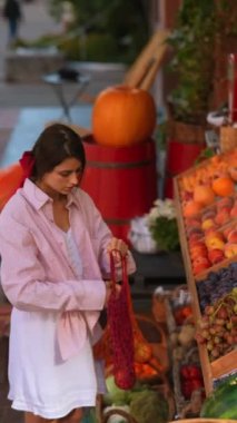 Avrupa çiftçi pazarındaki ışıl ışıl genç bir bayan meyveleri poşete koyarken çevre dostu uygulamalarla gurur duyuyor. Yüksek kalite 4k görüntü