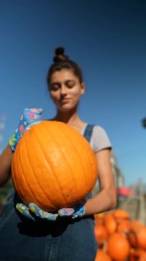 Hareketli bir pazarda, bir bayan çiftçi tutkuyla satılık balkabaklarını gösteriyor. Yüksek kalite 4k görüntü