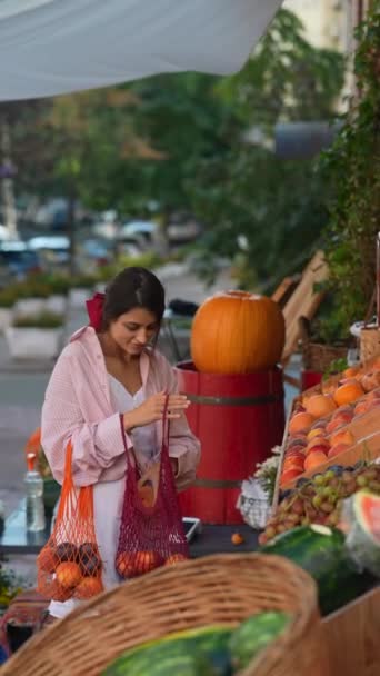 ヨーロッパの農家市場の放射性の若い女性は バッグに果物を整理しながら 環境に優しいプラクティスに誇りを持っています 高品質の4K映像 — ストック動画