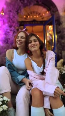 Bahçesinde mor çiçekleri olan iki çekici kadın. Yüksek kalite 4k görüntü