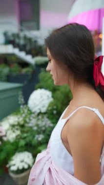 Zarif, kurdeleli bir kız, büyüleyici çiçekleriyle bahçeye girerek merdivenleri çıkıyor. Yüksek kalite 4k görüntü