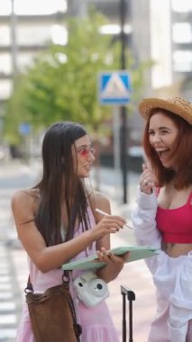 İki çağdaş kadın sohbet ederken ellerinde bavul ve çantalarla şehir sokaklarını keşfediyorlar. Yüksek kalite 4k görüntü
