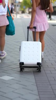 Elinde bavuluyla şehirde yürüyüş yapan iki hoş genç bayan. Yüksek kalite 4k görüntü