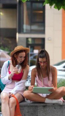 Işıl ışıl, modaya uygun bayanların sokakta tabletler ve soğuk içeceklerle oturduğu görülüyor. Yüksek kalite 4k görüntü