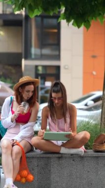 Şehir sokaklarında dinamik, şık kadınlar, tabletler ve soğuk içeceklerle rahatlıyor. Yüksek kalite 4k görüntü