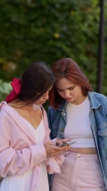 İki modaya uygun ve stil sahibi kız, her birinin akıllı telefonu var. Yüksek kalite 4k görüntü