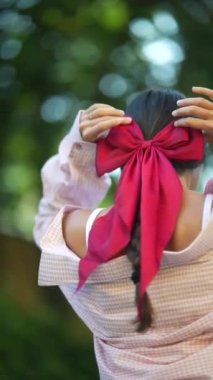 Saçında belirgin bir fiyonk olan genç bayanın arkasından bakın. Yüksek kalite 4k görüntü