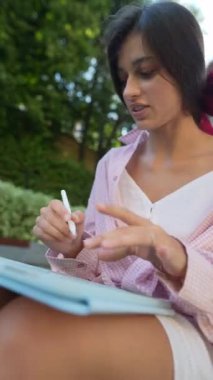 Yazın açık havada tabletle meşgul olan muhteşem, genç bir kadın. Yüksek kalite 4k görüntü