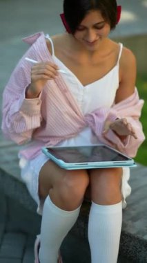 Güneşli bir yaz gününde tablet kullanan sevimli, genç bir bayan. Yüksek kalite 4k görüntü