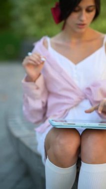 Yazın açık havada tabletle meşgul olan muhteşem, genç bir kadın. Yüksek kalite 4k görüntü