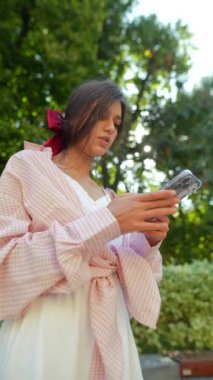 Şehir sokaklarında elinde telefonla güzel bir genç kadın. Yüksek kalite 4k görüntü