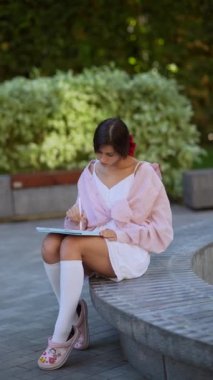 Parlak bir yaz gününde tabletle çalışan güzel, genç bir bayan. Yüksek kalite 4k görüntü