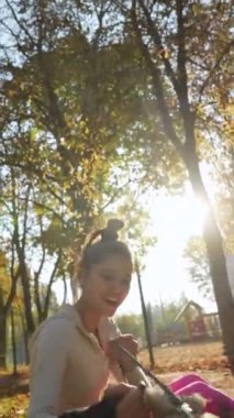 Sonbahar parkında, mutlu, genç bir kadın köpeğine sarılırken görülüyor. Yüksek kalite 4k görüntü