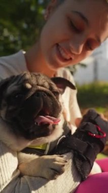 Sabah güneşi parlarken, hoş bir genç bayan köpeğiyle parkta eğleniyor. Yüksek kalite 4k görüntü