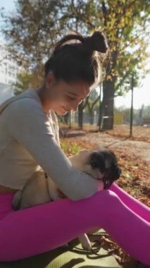 Sonbahar parkında, mutlu genç bir bayan köpeğini gülümseyerek kucaklıyor. Yüksek kalite 4k görüntü