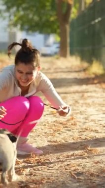 Sonbahar gününün güneşinin tadını çıkaran güzel bir kız, pug köpeğiyle eğleniyor. Yüksek kalite 4k görüntü