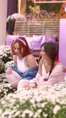 Çiçeklerin arasında, iki güzel arkadaş merdivenlerde oturuyor. Yüksek kalite 4k görüntü