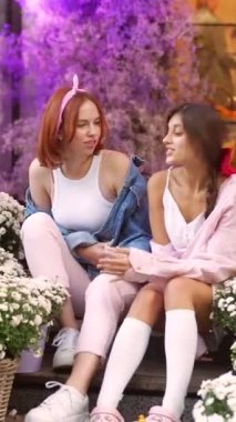 Çiçeklerin ortasında iki güzel arkadaş merdivenlerde dinleniyor. Yüksek kalite 4k görüntü