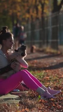 Sonbahar parkında, mutlu genç bir bayan köpeğini gülümseyerek kucaklıyor. Yüksek kalite 4k görüntü