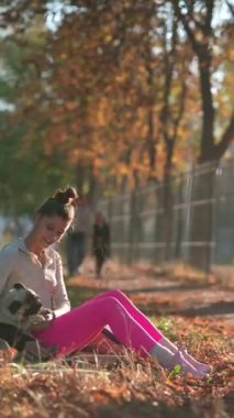 Sonbahar parkında, genç bir bayan sabah yürüyüşü sırasında köpeğiyle oynar. Yüksek kalite 4k görüntü