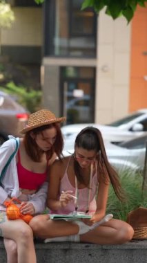 Açık alanda, iki güzel kız sokakta bir tablet kullanıyor. Yüksek kalite 4k görüntü