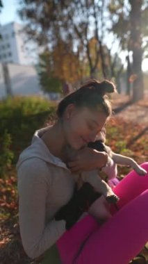 Neşeli genç bir kadın bir sonbahar günü parkta köpeğine sarılıyor. Yüksek kalite 4k görüntü