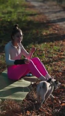 Bir kız ve köpeği, sonbahar parkında parlak atletik giysiler giyen genç bir bayanla yürüyüş yaparken görülüyor. Yüksek kalite 4k görüntü