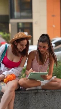Güzel genç bayanlar bir yaz günü açık havada bir tablette internetten çalışıyorlar. Yüksek kalite 4k görüntü