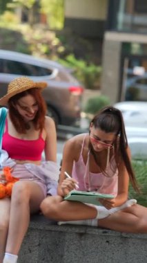 Çevrimiçi işlerle meşgul olan iki tatlı genç kadın, bir tabletle yaz günlerini en iyi şekilde geçiriyorlar. Yüksek kalite 4k görüntü