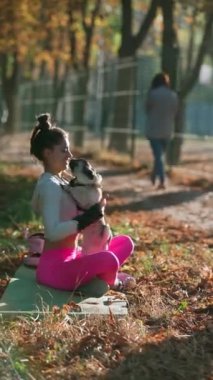 Sonbaharda güneşli bir gün, neşeli bir kız parkta köpeğine sarılıyor. Yüksek kalite 4k görüntü