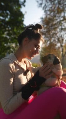 Muhteşem genç bir bayan ve köpeği parkta sonbahar yapraklarının arasında oturuyorlar. Yüksek kalite 4k görüntü