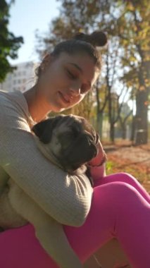 Sabah güneşi parkı aydınlatırken, büyüleyici genç bir kadın oyun yoluyla köpeğiyle kaliteli vakit geçirmekten zevk alıyor. Yüksek kalite 4k görüntü