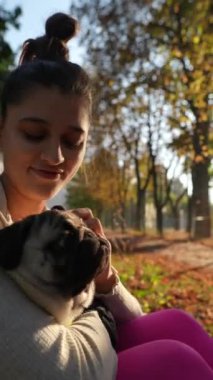 Güneşli bir sabahta parkta, sevimli genç bir bayan köpeğiyle eğlenceli aktiviteler yapıyor. Yüksek kalite 4k görüntü