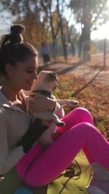 Bir sonbahar günü, neşeli genç bir bayan parkta köpeğini kucaklıyor. Yüksek kalite 4k görüntü