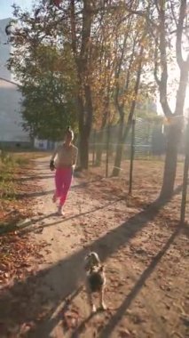 Parkta, sportif bir kız pug köpeğiyle koşuyor. Yüksek kalite 4k görüntü