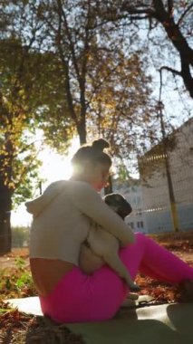 Neşeli genç bir kadın bir sonbahar günü parkta köpeğine sarılıyor. Yüksek kalite 4k görüntü