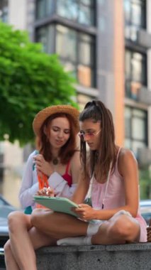 Şehir sokaklarında, iki muhteşem genç bayan online işler için tablet kullanıyor. Yüksek kalite 4k görüntü