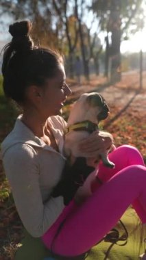Sonbahar parkında, mutlu, genç bir kadın köpeğine sarılırken görülüyor. Yüksek kalite 4k görüntü