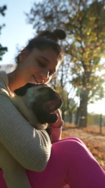 Parkların ortasında sonbahar yaprakları arasında güzel bir kadın köpeğiyle biraz vakit geçiriyor. Yüksek kalite 4k görüntü