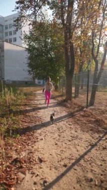 Yanında pug köpeği olan enerjik genç bir kadın parkta koşuyor. Yüksek kalite 4k görüntü
