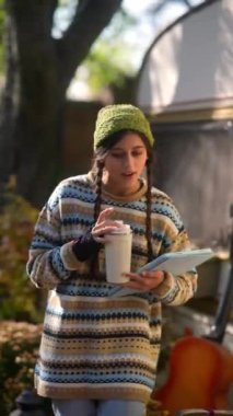 Güneşli bir sonbahar gününde, hayat dolu genç bir hippi kadın açık havada bir tablet kullanıyor. Yüksek kalite 4k görüntü