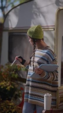 Sonbahar yaprakları arasında, hippi bir kız güzel bir karavanın yanında manzaranın tadını çıkarırken tabletle çalışmalarını sergiliyor. Yüksek kalite 4k görüntü