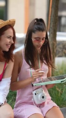 Elinde tablet ve meyvelerle iki genç ve enerjik bayan şehir sokaklarında mola veriyor. Yüksek kalite 4k görüntü