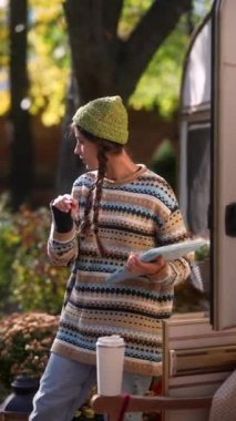 Hippi cazibesiyle, neşeli genç bir kadın, güneşli bir sonbahar gününde açık havada tablet üzerinde çalışıyor. Yüksek kalite 4k görüntü