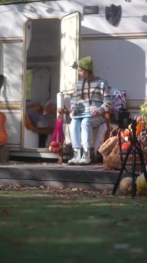 Hippi cazibesiyle, neşeli genç bir kadın, güneşli bir sonbahar gününde açık havada tablet üzerinde çalışıyor. Yüksek kalite 4k görüntü