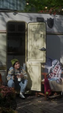 Neşeli bir hippi kız karavanın yanında oturur ve güzel sonbahar havasının tadını çıkarır. Yüksek kalite 4k görüntü