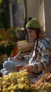 Gerçek hipster tarzında, büyüleyici ve genç bir kadın güneşli bir sonbahar gününde tabletine kendini adamıştır. Yüksek kalite 4k görüntü