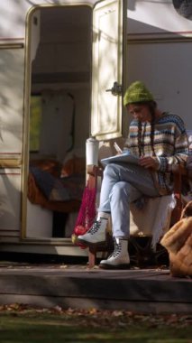 Sonbahar bahçesinde, genç ve güzel bir hippi kadın sıcak bir içecek yudumlarken tabletinde çalışıyor. Yüksek kalite 4k görüntü